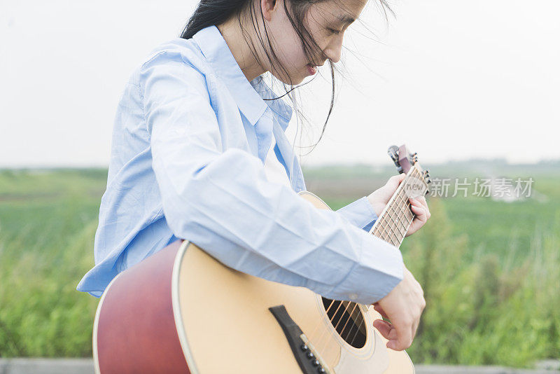 女人的手在田野里弹吉他的特写