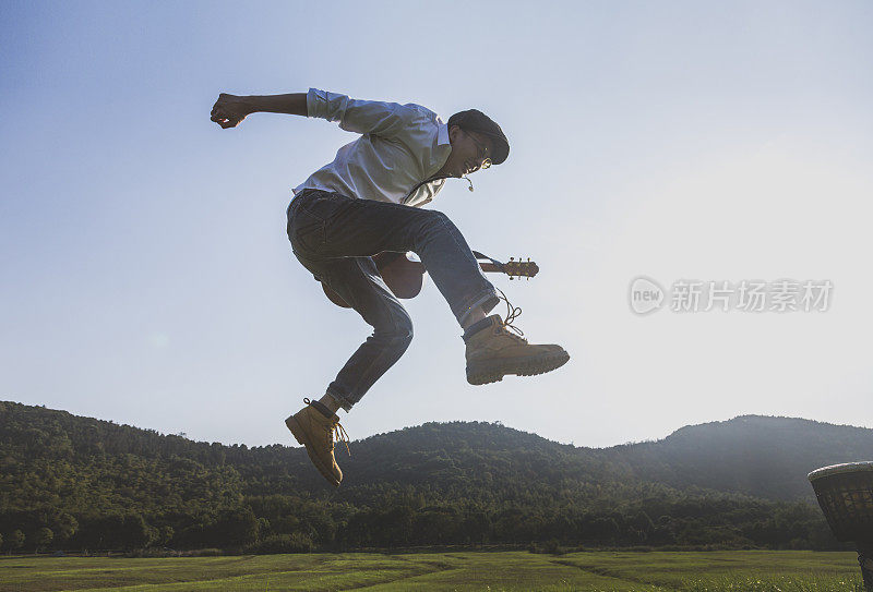 年轻有权势的男人拿着吉他在球场上跳来跳去