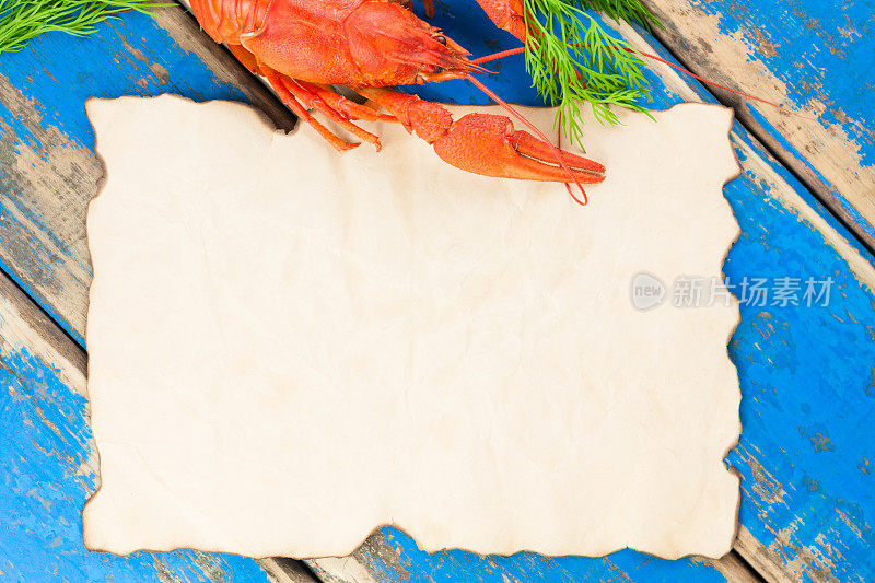 一只整只的红煮小龙虾，带嫩枝的新鲜的绿色小茴香，旁边是一张空烤盘，放在古老的乡村的蓝色木板上