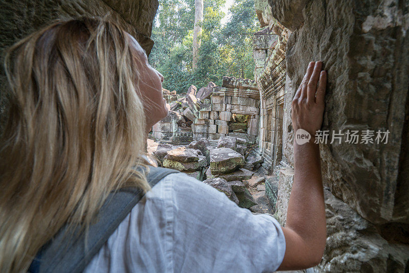 年轻女子沉思古庙，旅行发现冒险概念在热带度假;金发游客女性参观古老的废墟