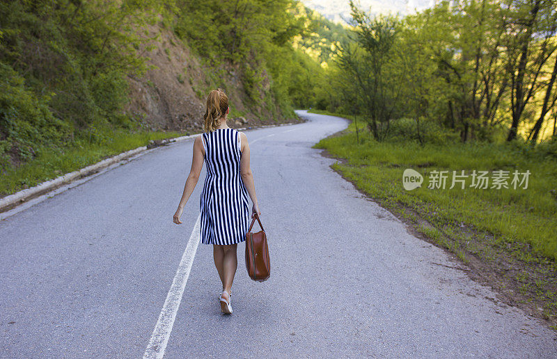 女旅行家提着行李箱在路上行走