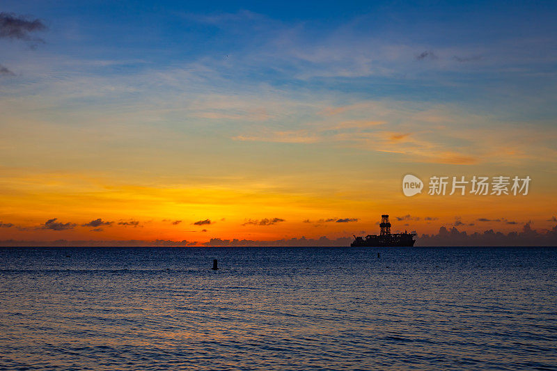 日落在加勒比海阿鲁巴西海岸和石油勘探船的剪影