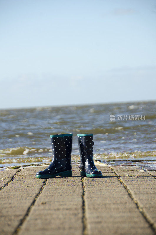 蓝色的孩子们的橡胶靴子独自留在海里，海水很快就会淹没它们