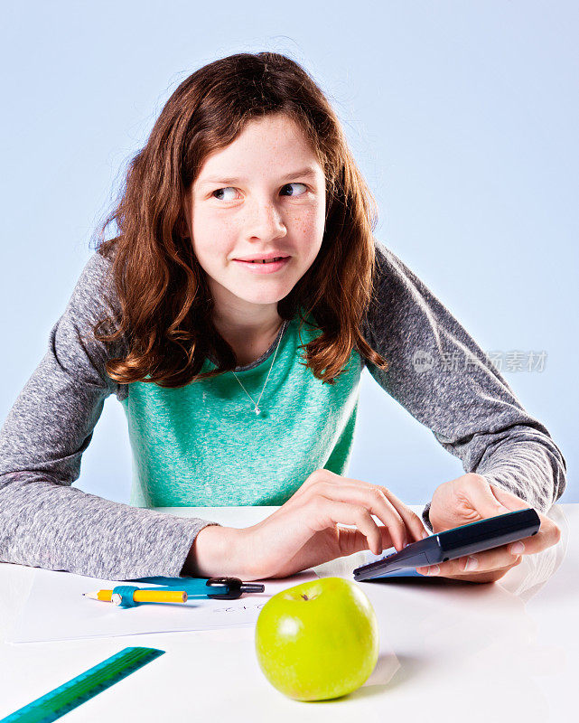 可爱的十来岁的女孩用计算器淘气地看着旁边