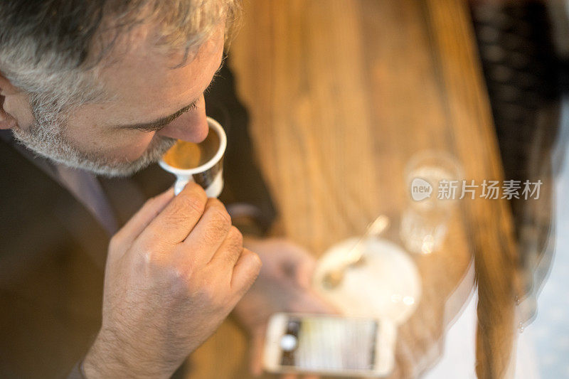 成熟的男人在酒吧喝咖啡和用手机