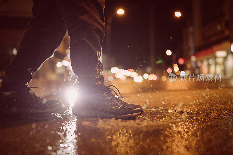 一个不认识的人在雨夜踏进水坑