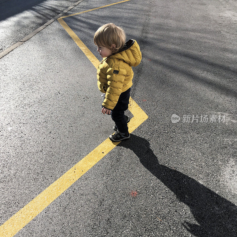 一个蹒跚学步的孩子走在街上的照片