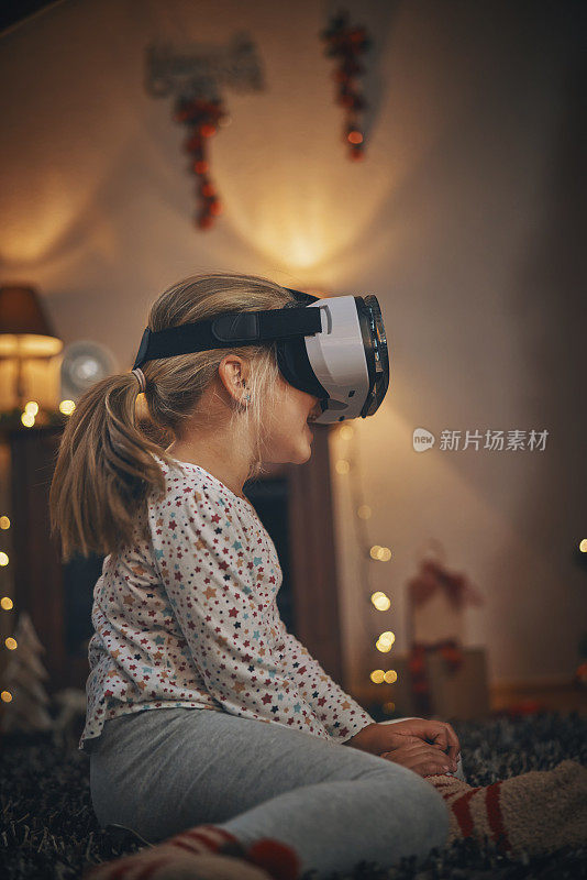 在舒适的圣诞氛围中，小女孩在客厅玩VR眼镜