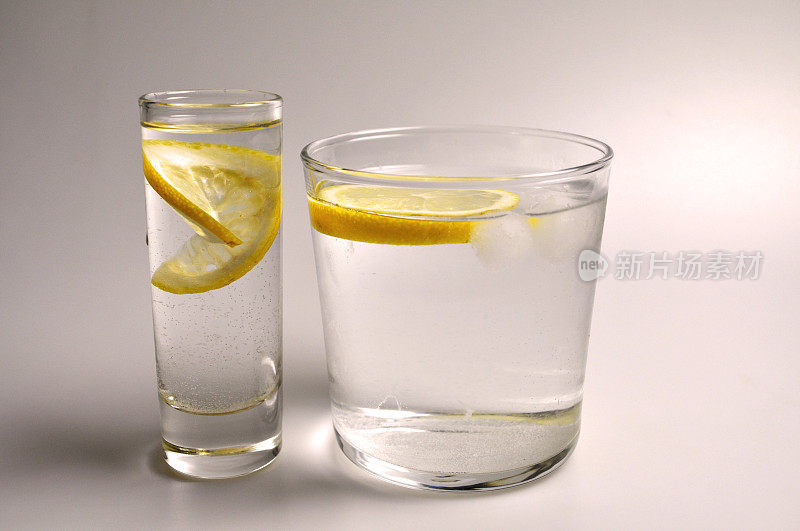 两个透明玻璃杯，装有无色液体-水，酒精