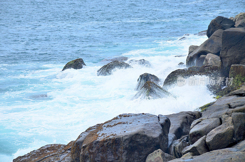一波海浪拍打着海岸的石头