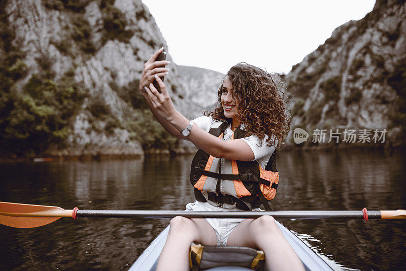 可爱的女孩在湖皮划艇之旅中自拍