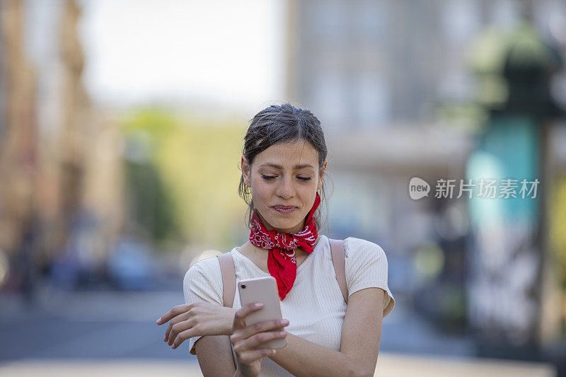 一名年轻女子正带着她的智能手机走在城市的路上