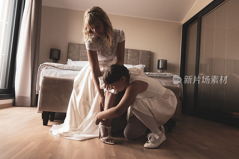 年轻的伴娘帮助新娘穿上婚礼鞋