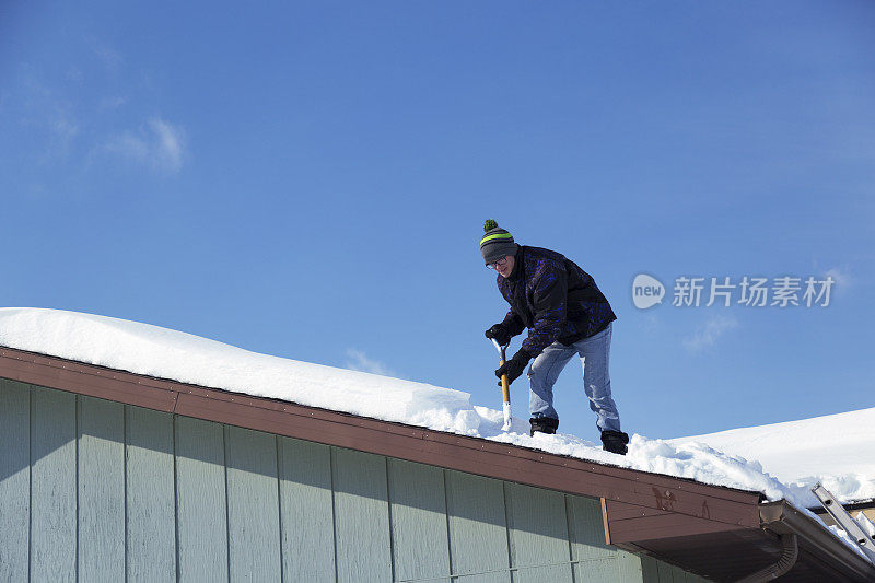 一名男子正在铲屋顶上的积雪