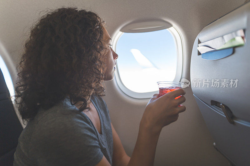飞机上的旅客正在享受一杯饮料