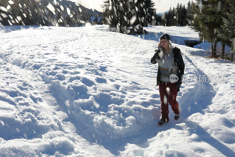 一个年轻女子一边打电话一边走在雪道上