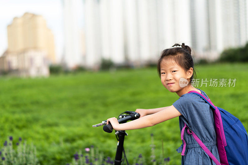 一个亚洲小女孩在草坪上骑自行车