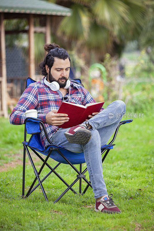 正面的年轻潮人阅读在一个公园里