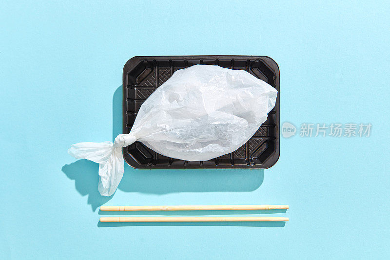饭盒里装着鱼，塑料袋装着木筷子。