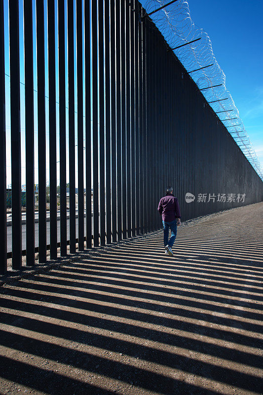 加州，卡莱西科:一名男子走过新设的美墨边境屏障