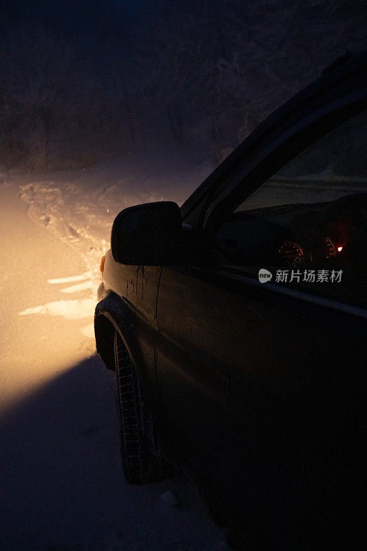 司机POV在积雪覆盖的道路上行驶，初雪飘落。被前灯和前车的红绿灯照亮的路。