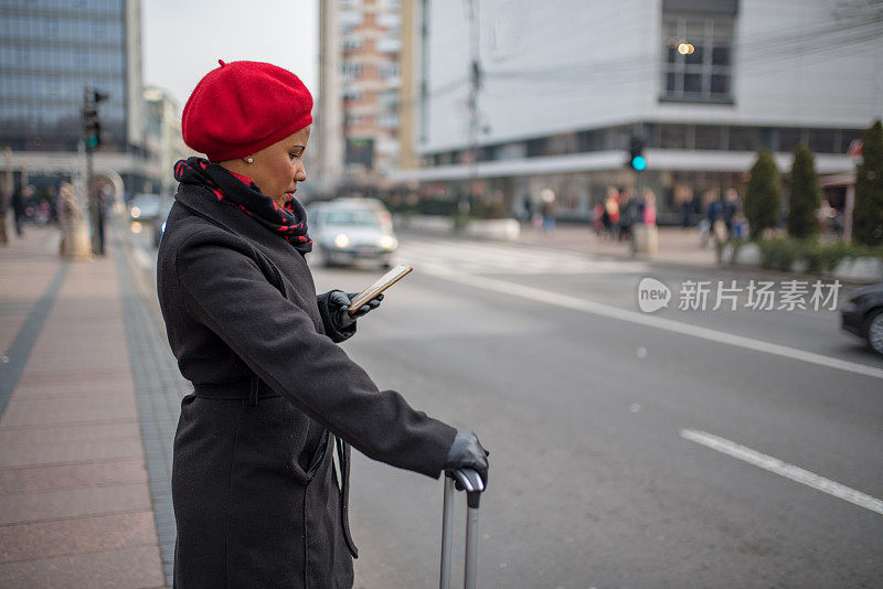 漂亮的肤色女人使用手机应用程序得到一个出租车