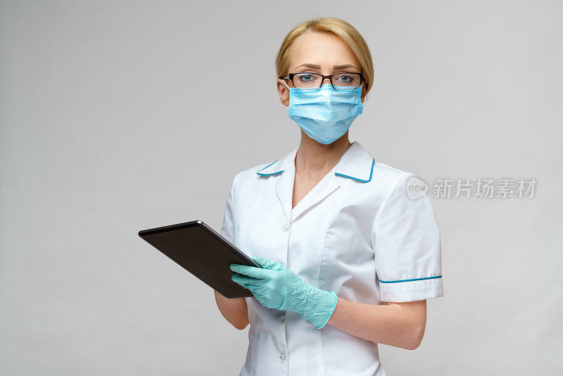 医生护士女人戴着防护口罩和手套拿着平板电脑