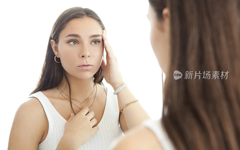 年轻女子在镜子上看她的痤疮疤痕