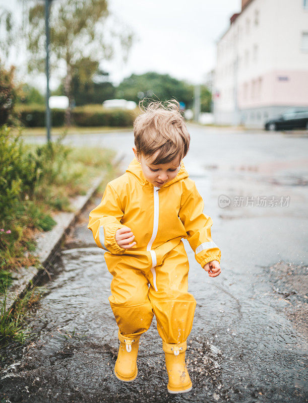 小男孩在雨中玩耍，跳进水里画画