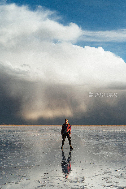 玻利维亚乌尤尼盐湖，一名年轻的白人男子在欣赏日落