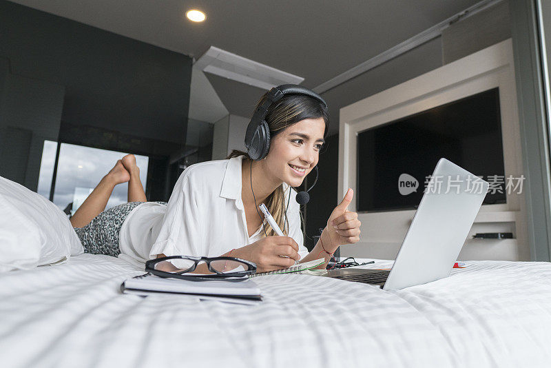 一名妇女在床上使用笔记本电脑进行COVID-19隔离工作