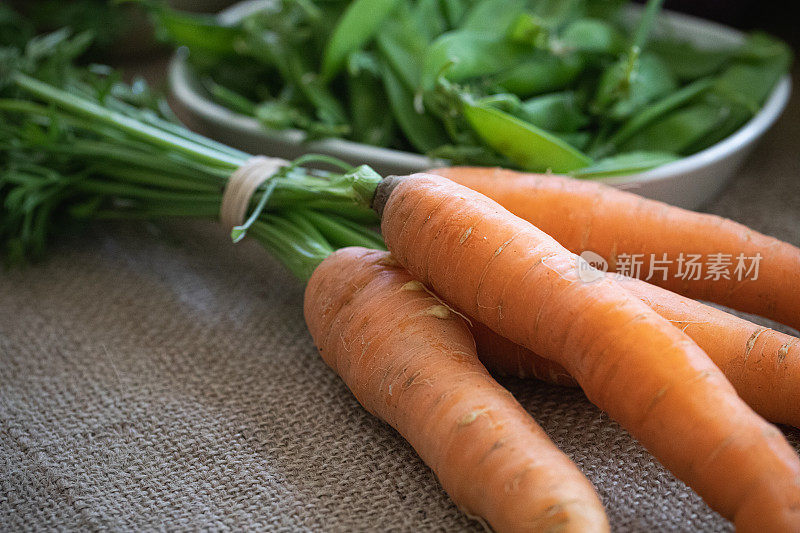 新鲜采摘的胡萝卜和雪豆的特写。