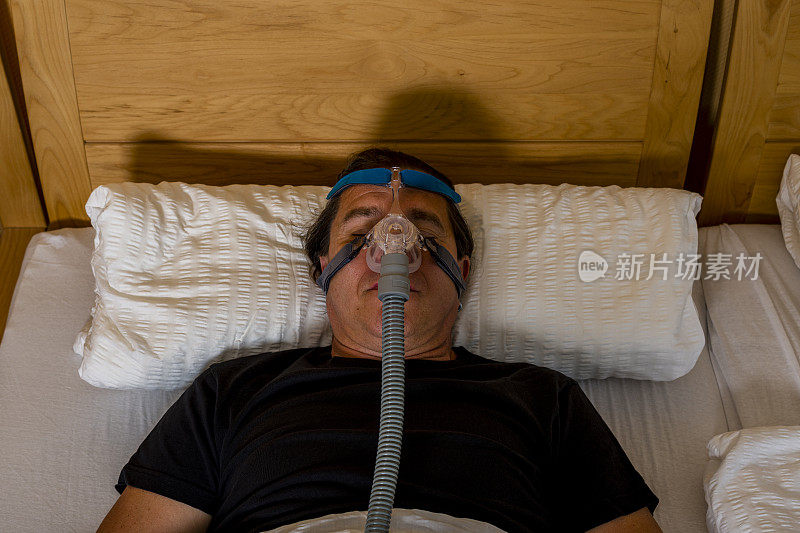 由于阻塞性睡眠呼吸暂停，男子带着cpap面罩睡觉