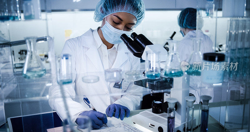 研究DNA突变的多种族女性团队。在防护服中使用显微镜