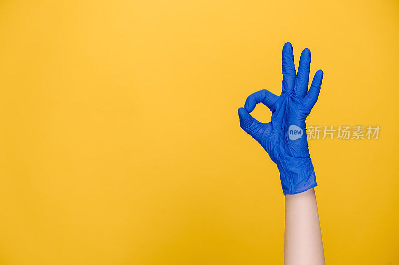 男性手在医用防护手套的特写显示ok标志，孤立在黄色工作室背景与拷贝空间，表达庆祝和胜利。肢体语言的概念。手势语