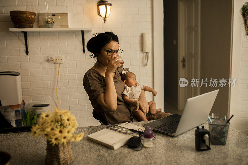 工作的亚洲母亲在家里抱着他可爱的宝宝