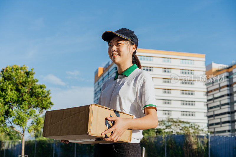 一个亚洲的中国女送货员拿着一个纸板箱