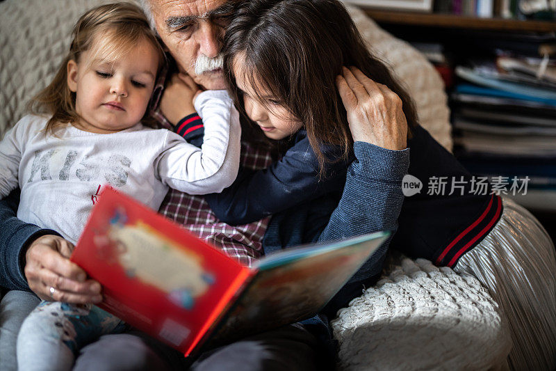 可爱的小女孩和爷爷一起读儿童读物