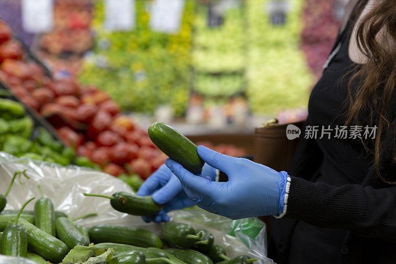 女性戴着防护手套在超市购物