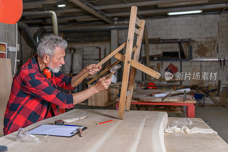 木匠师傅正在打磨一把木椅的木质表面。