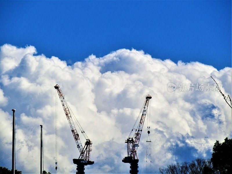 日本。2月。两座建筑起重机与蓝天上的白云交流。