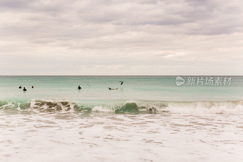 2021年1月的中午，冲浪者在蓝绿色的海浪上冲浪，横扫佛罗里达州的朱诺海滩
