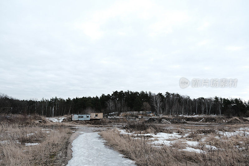 被遗弃的建筑工人在路的尽头的棚屋下融化的雪