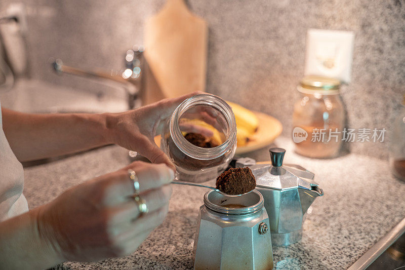 厨房里的一位妇女用可重复使用的容器做意大利咖啡