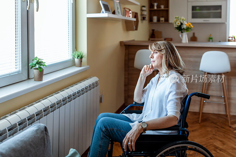 残疾的成年妇女坐在轮椅上呆在家里的客厅里。