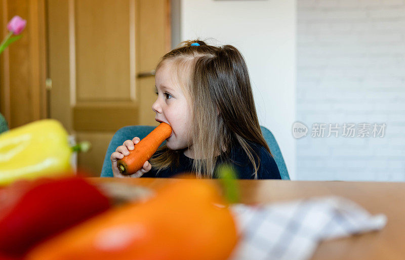 小女孩在厨房里吃胡萝卜