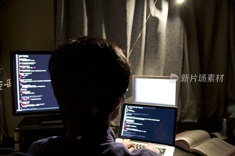一个年轻的亚洲程序员在一间黑屋子里编程
