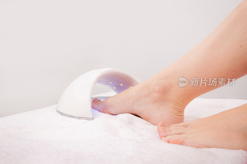 一位妇女用紫外线晒脚趾甲。