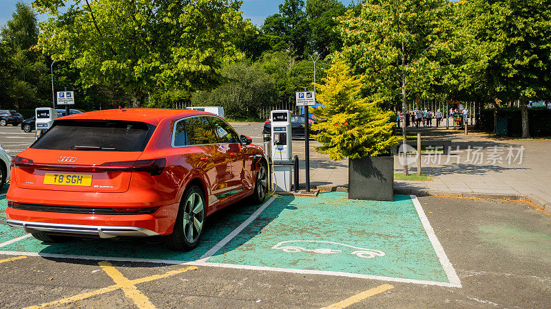 红色奥迪e-tron电动车在停车场的一个充电站充电