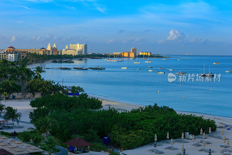 日出时分，南加勒比海阿鲁巴棕榈海滩的旅游胜地。海边停泊着几家海滩旅馆和几艘船，但几乎没有人在海滩上;显然现在还为时过早。